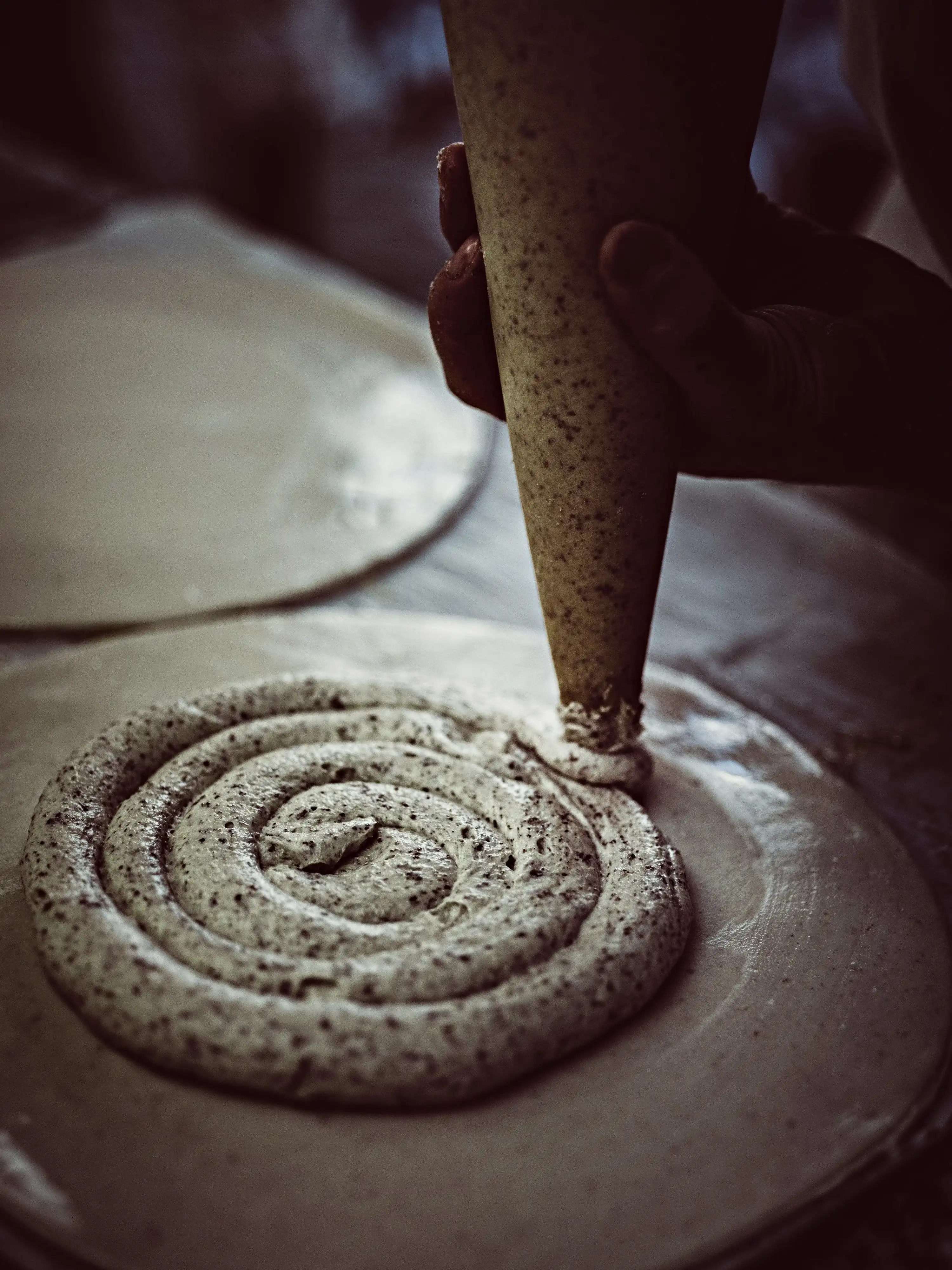 Pastry chef applying frangipane in a pouch onto a disk of dough, stage of preparing an artisanal galette des rois.