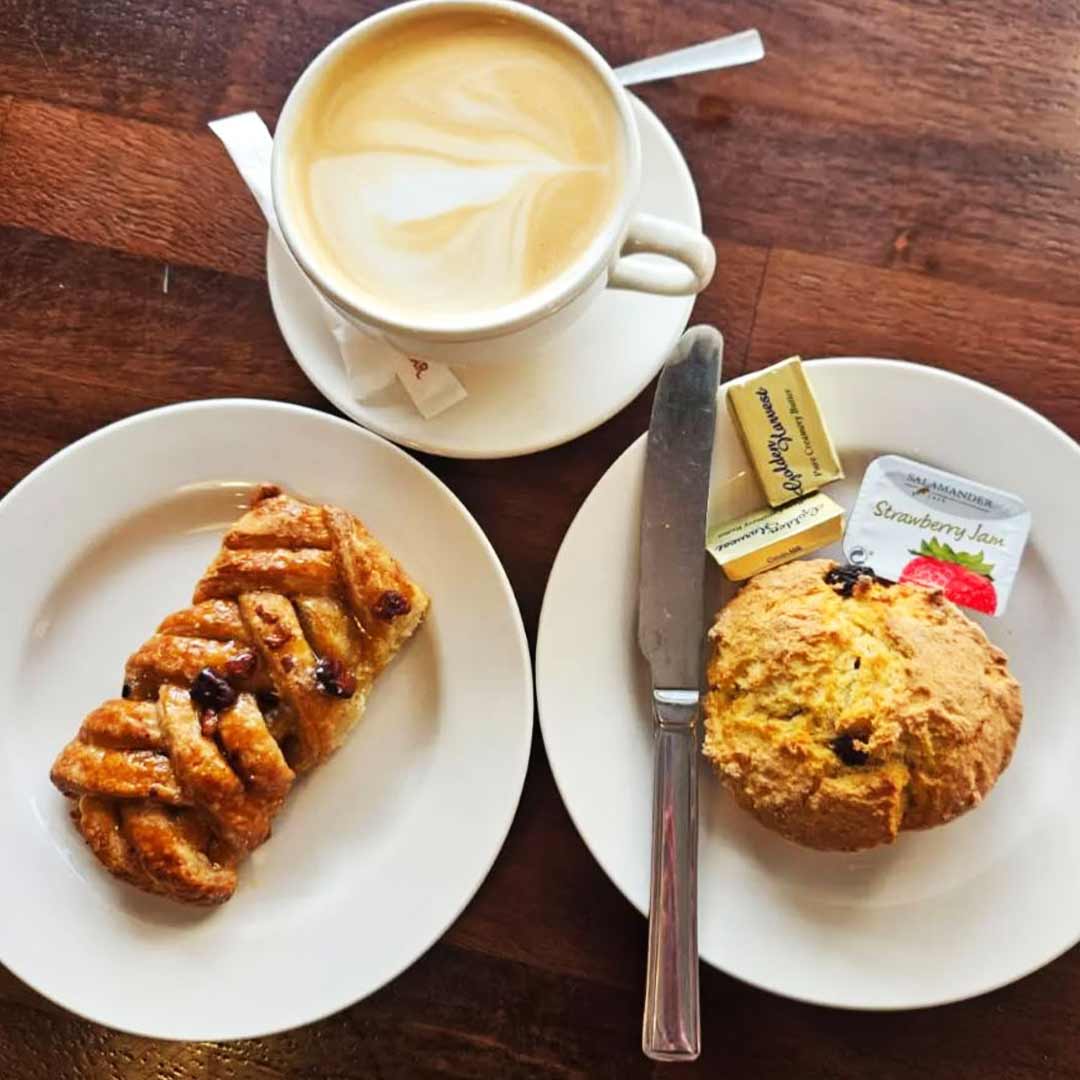 A coffee, Danish Pastry, and a Scone are displayed on a table