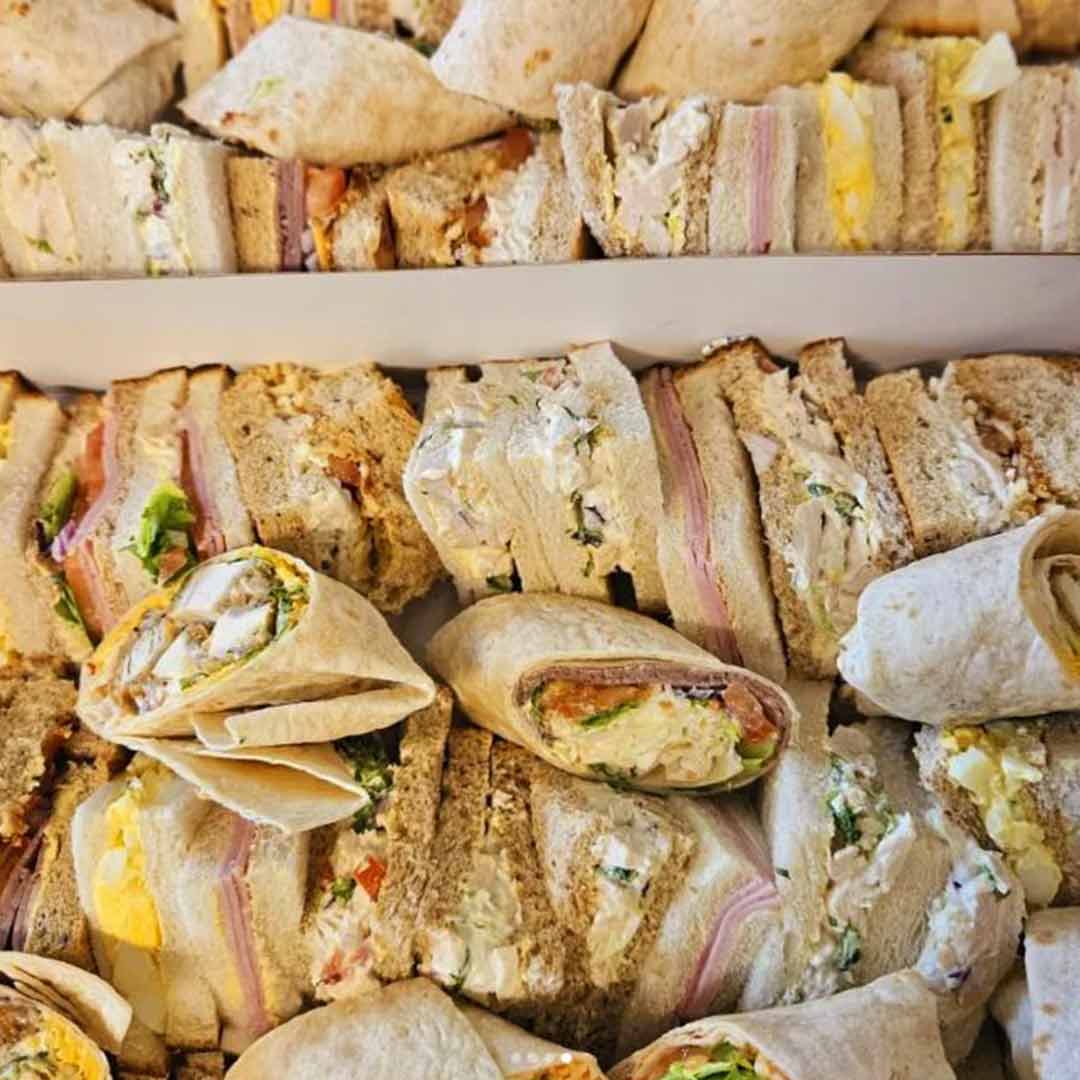 Roots Catering - A tray of sandwiches, wraps, and rolls packed with various fillings