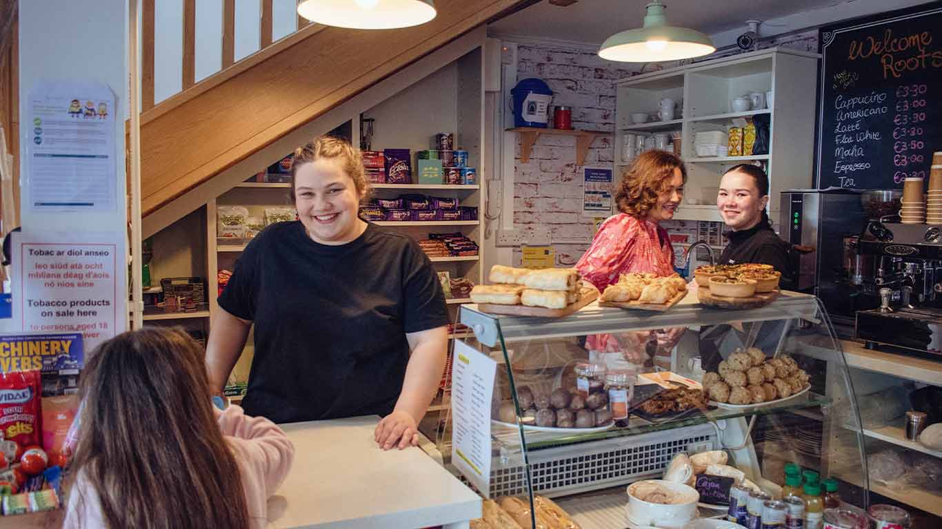 A shop volunteer smiles as she serves a young customer
