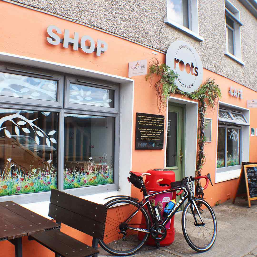 A bicycle is parked outside Roots Shop & Cafe