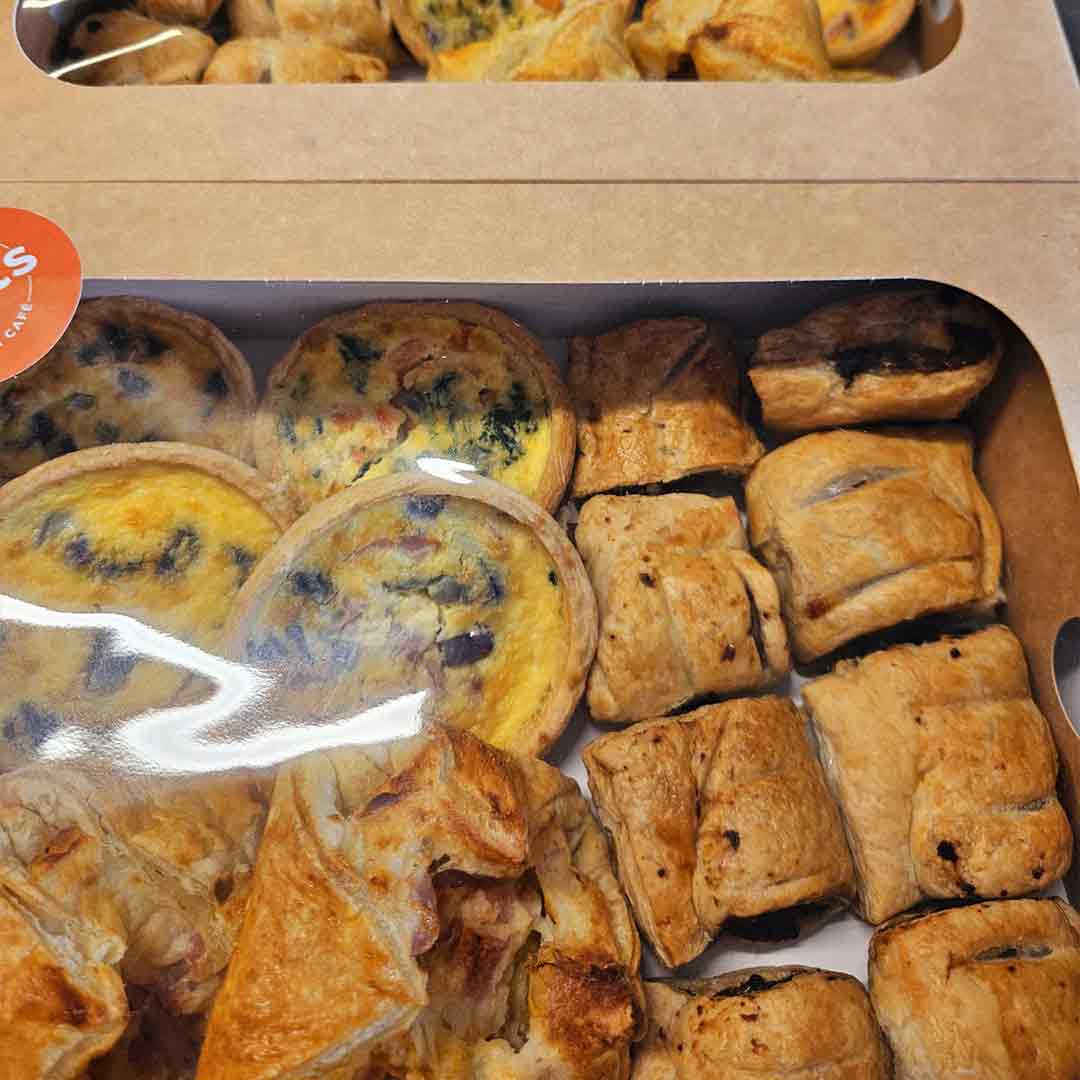 A selection box filled with mini-jambons, sausage rolls, and mini-tarts