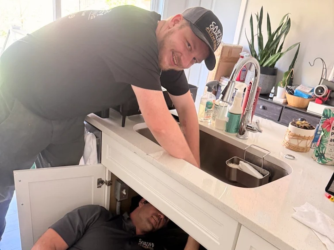 Carter Quality Plumbing technicians working on a kitchen sink fixture