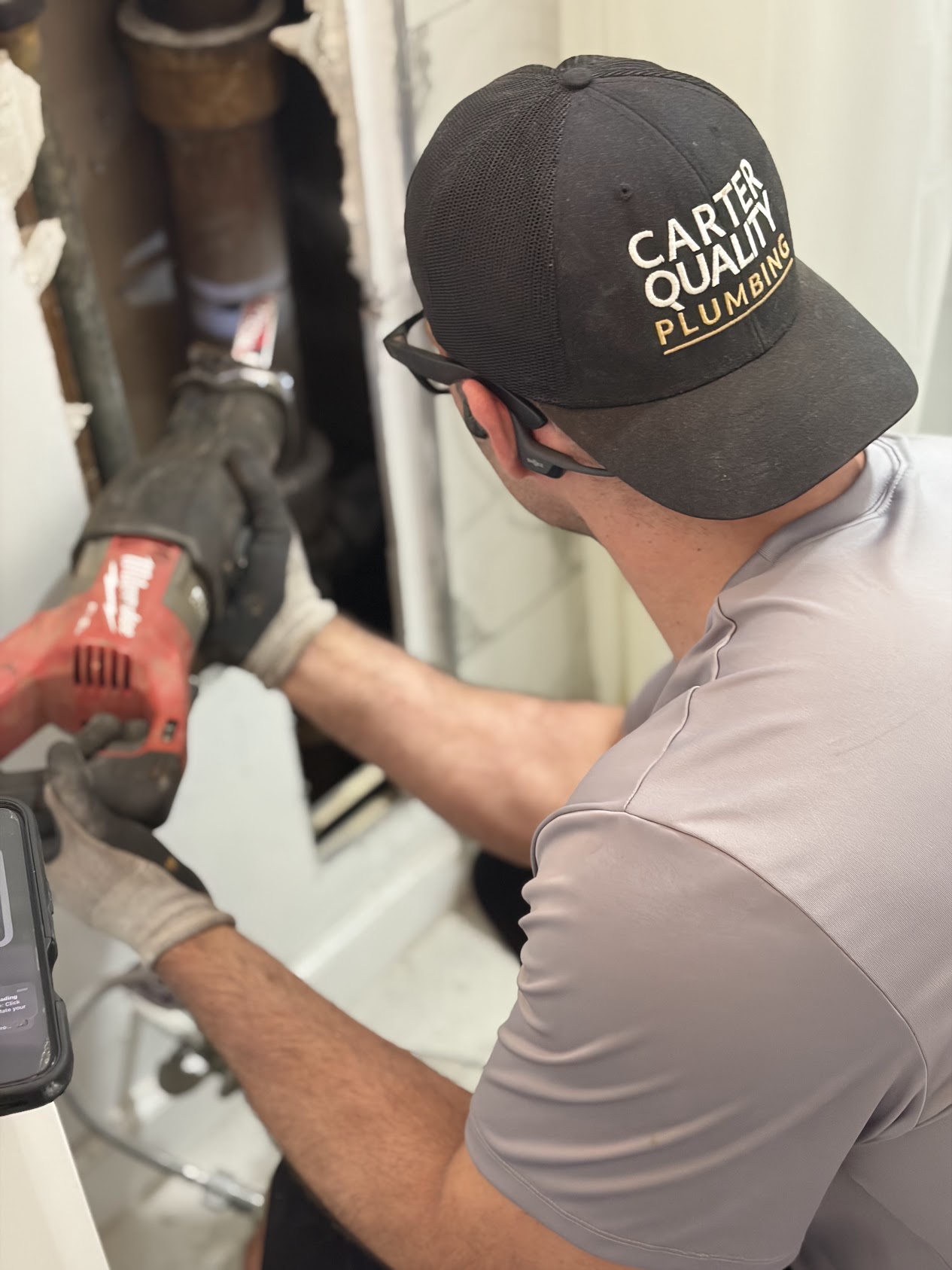 Carter Quality Plumbing technician wearing a branded Carter Quality Plumbing hat while performing residential plumbing work