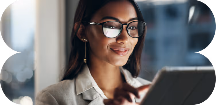 A woman with glasses looks at a tablet