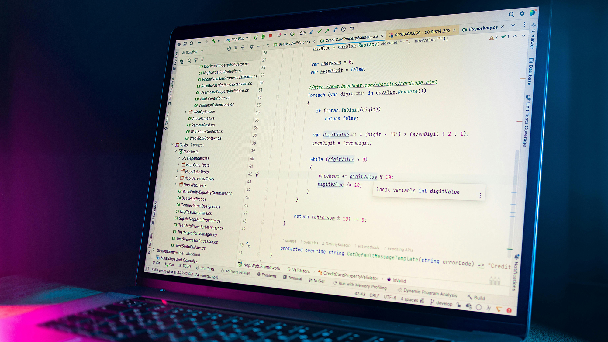 Laptop screen displaying C# code in an integrated development environment with a dark blue and purple background.