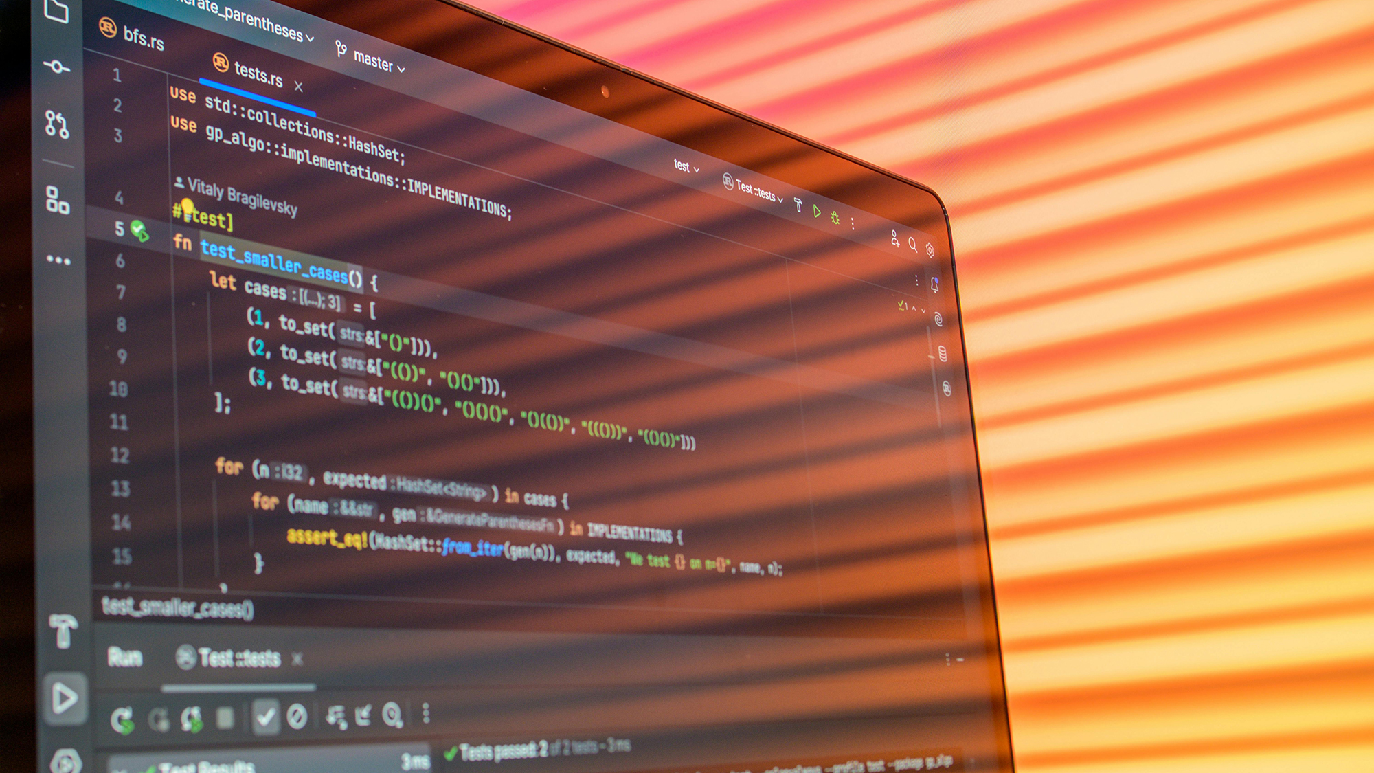 Close-up of a computer screen displaying Rust programming code with shadow lines from window blinds.