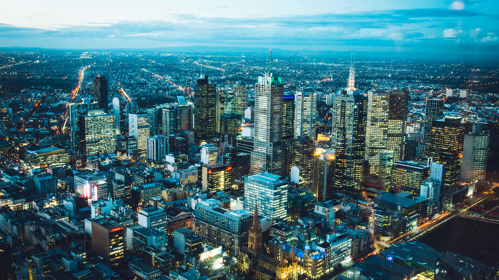 Aerial night view of a city skyline with illuminated skyscrapers and streets.
