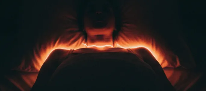 Person lying awake in bed at night, restless and unable to fall asleep