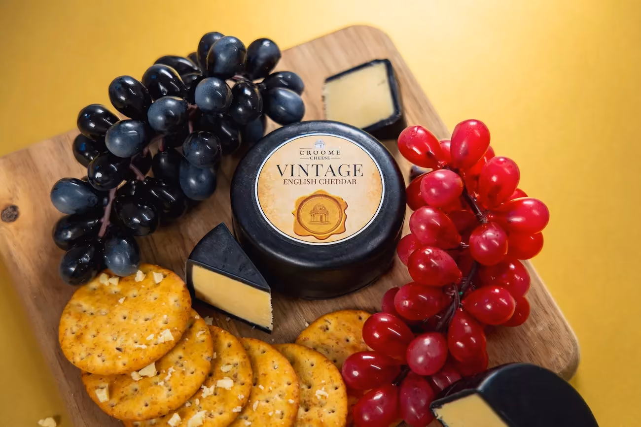 Vintage english cheddar cheese on a cheese board with grapes and biscuits. 