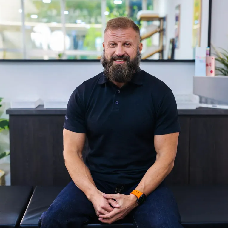 Dr Will Kalla, a neck pain specialist in Singapore, sitting in his structural chiropractic clinic.