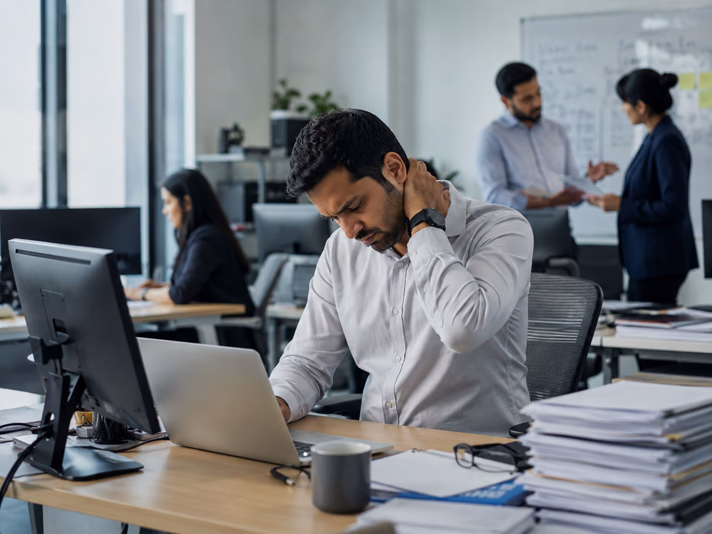 Office worker in a Singapore workplace experiencing desk-related neck pain.
