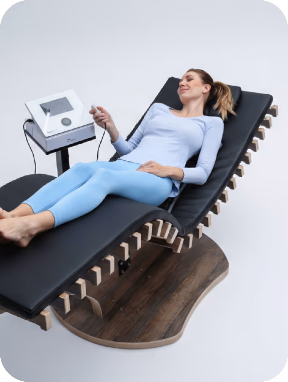 Frau entspannt auf einem ergonomischen Massageliege mit einem Handgerät neben ihr.