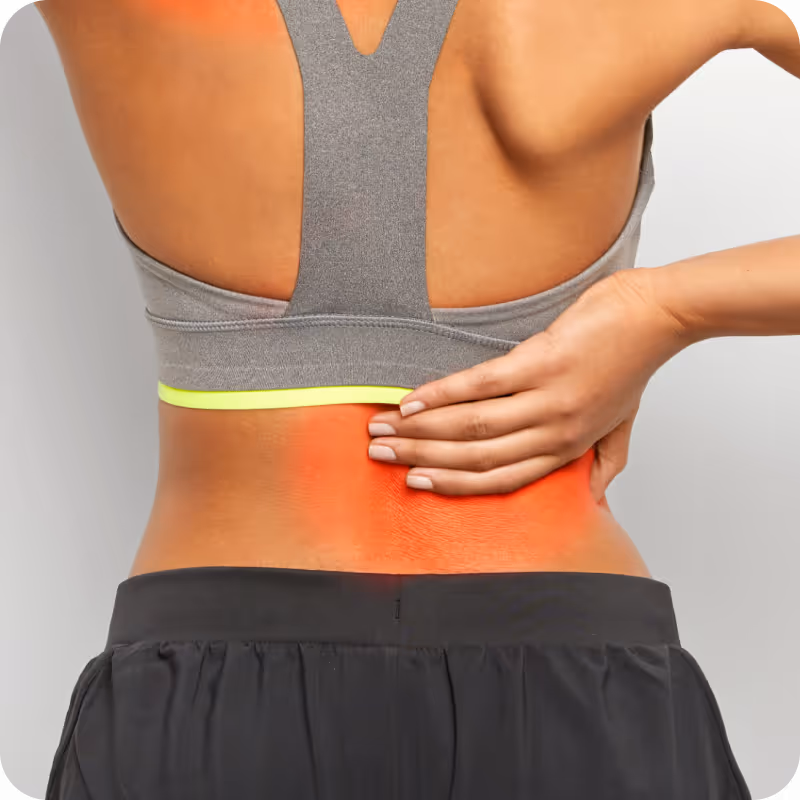 Frau hält ihren unteren Rücken mit einer Hand, Bereich rot markiert für Schmerzen oder Entzündung.