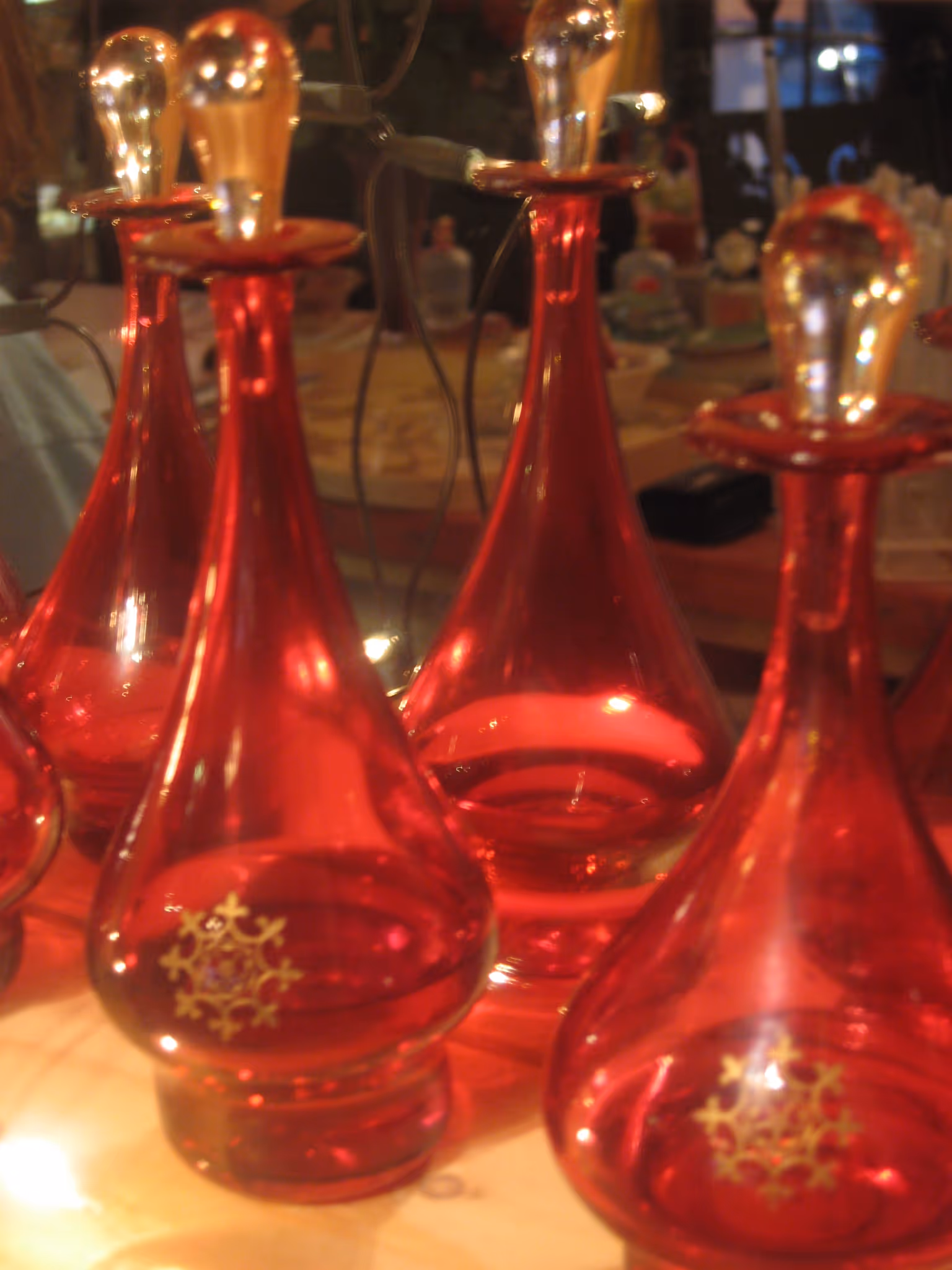 Several red glass decanters with clear stoppers arranged on a wooden surface.