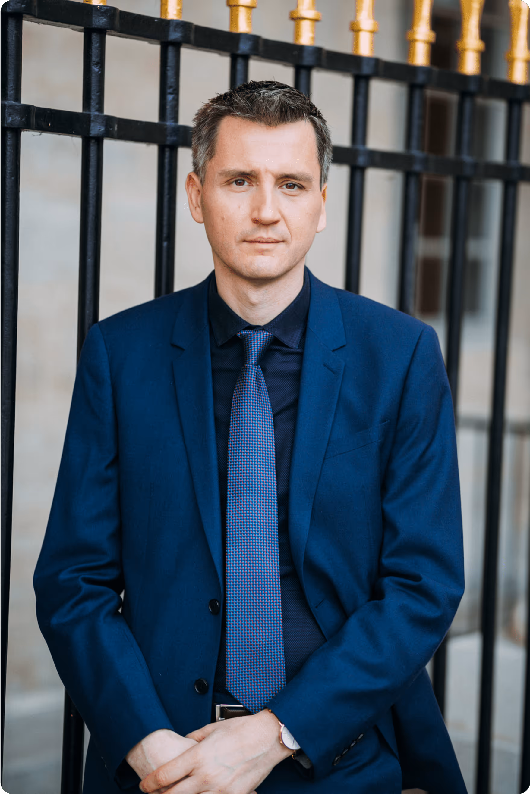 L'agent immobilier Vasic Dino en costume, posant devant une grille en fer forgé