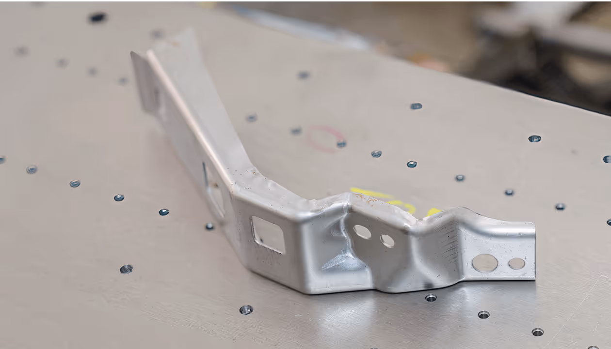 Metallgitterbox auf hellem Hallenboden, mit Holzpalette als Boden, in leeren, gut beleuchteten Lagerraum.