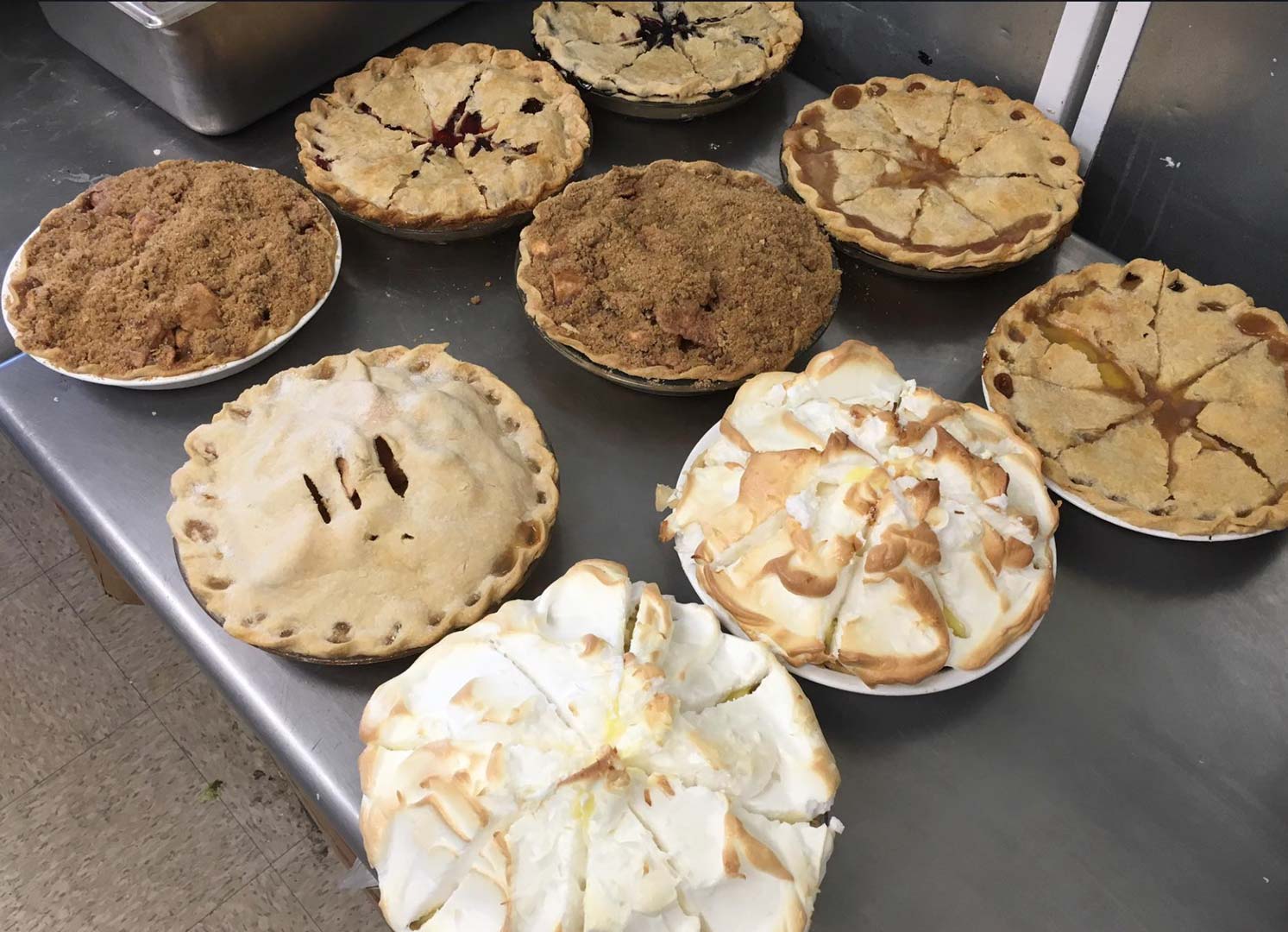 Several freshly baked pies arranged neatly on a kitchen countertop, showcasing a variety of flavors and crust designs.