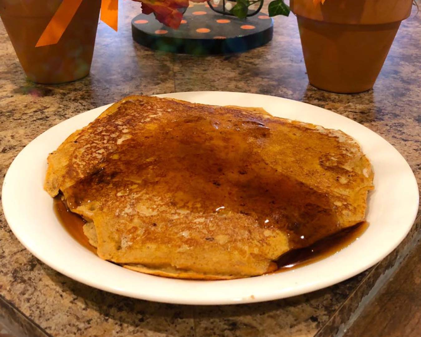 A platter of pancakes topped with maple syrup.