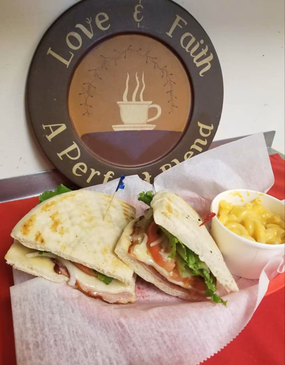 A sandwich alongside a serving of macaroni and cheese is displayed on a table.