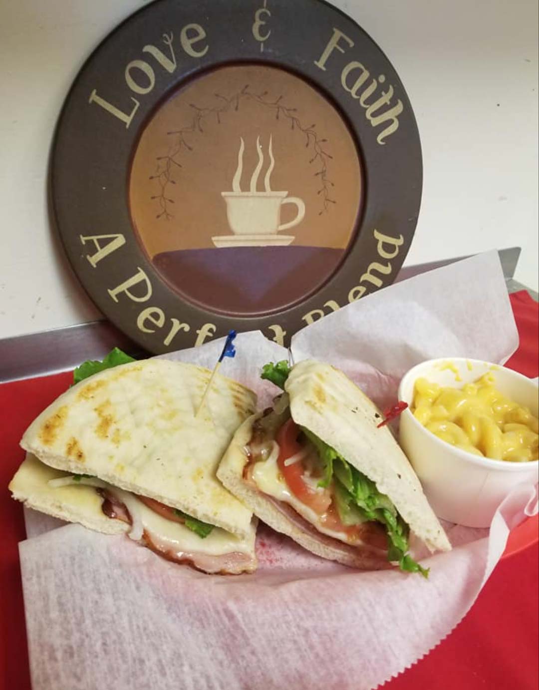 A sandwich alongside a serving of macaroni and cheese is displayed on a table.