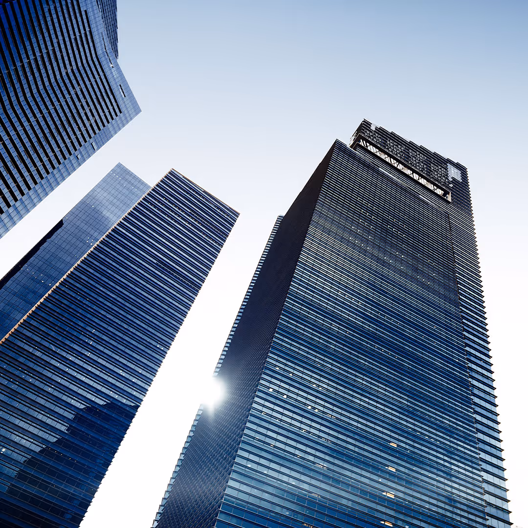 Alti grattacieli di vetro con riflessi del sole su un cielo chiaro.
