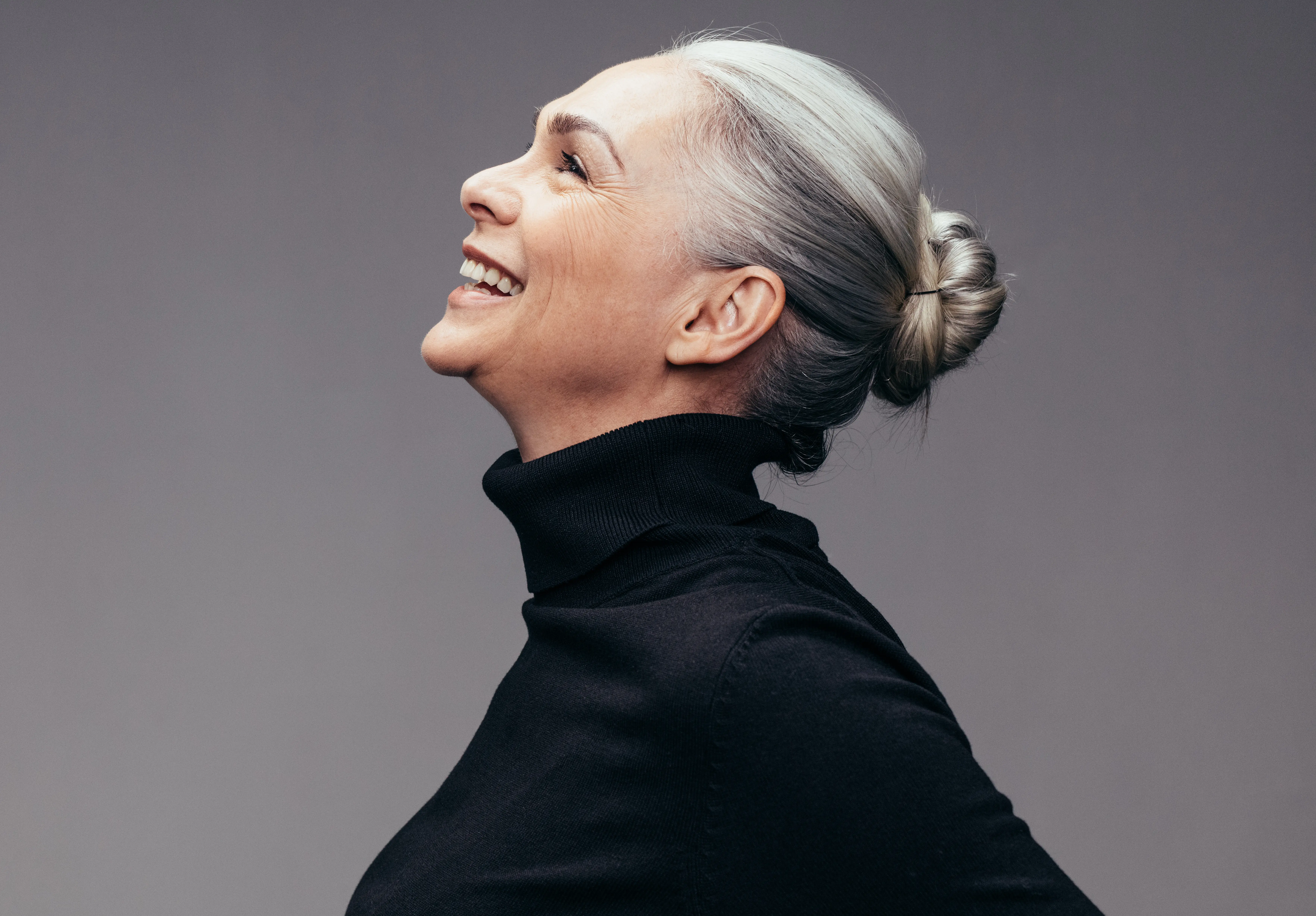 A woman with grey hair wearing a black turtle neck sweater.