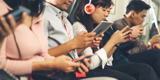 Close-up shot of commuters in a subway immersing in their mobile devices.