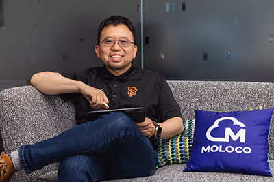 moloco employee sitting on the couch beside a moloco pillow