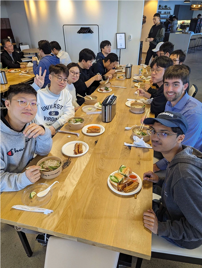 Group of Moloco interns seated at a long table, eating various Asian-style foods.