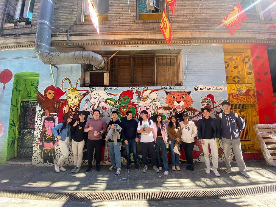Group of Moloco interns posing in front of a vibrant mural depicting zodiac warriors, 2021.