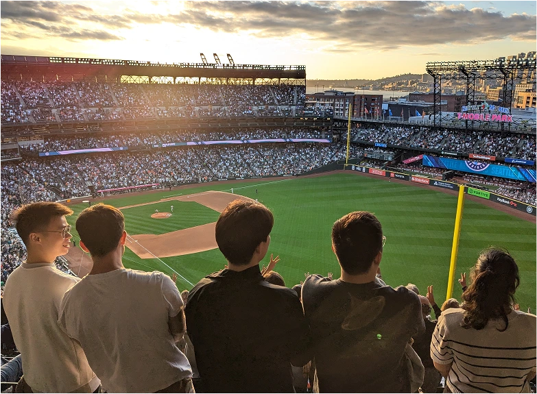 Full baseball stadium at sunset with spectators, including Moloco interns in the foreground.