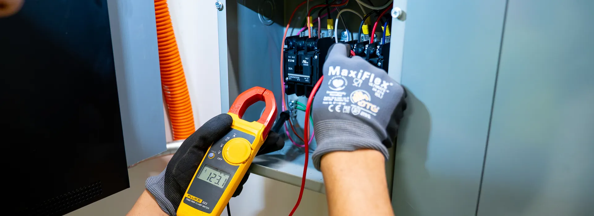KB Electric service technician testing a commercial electrical panel with a clamp meter