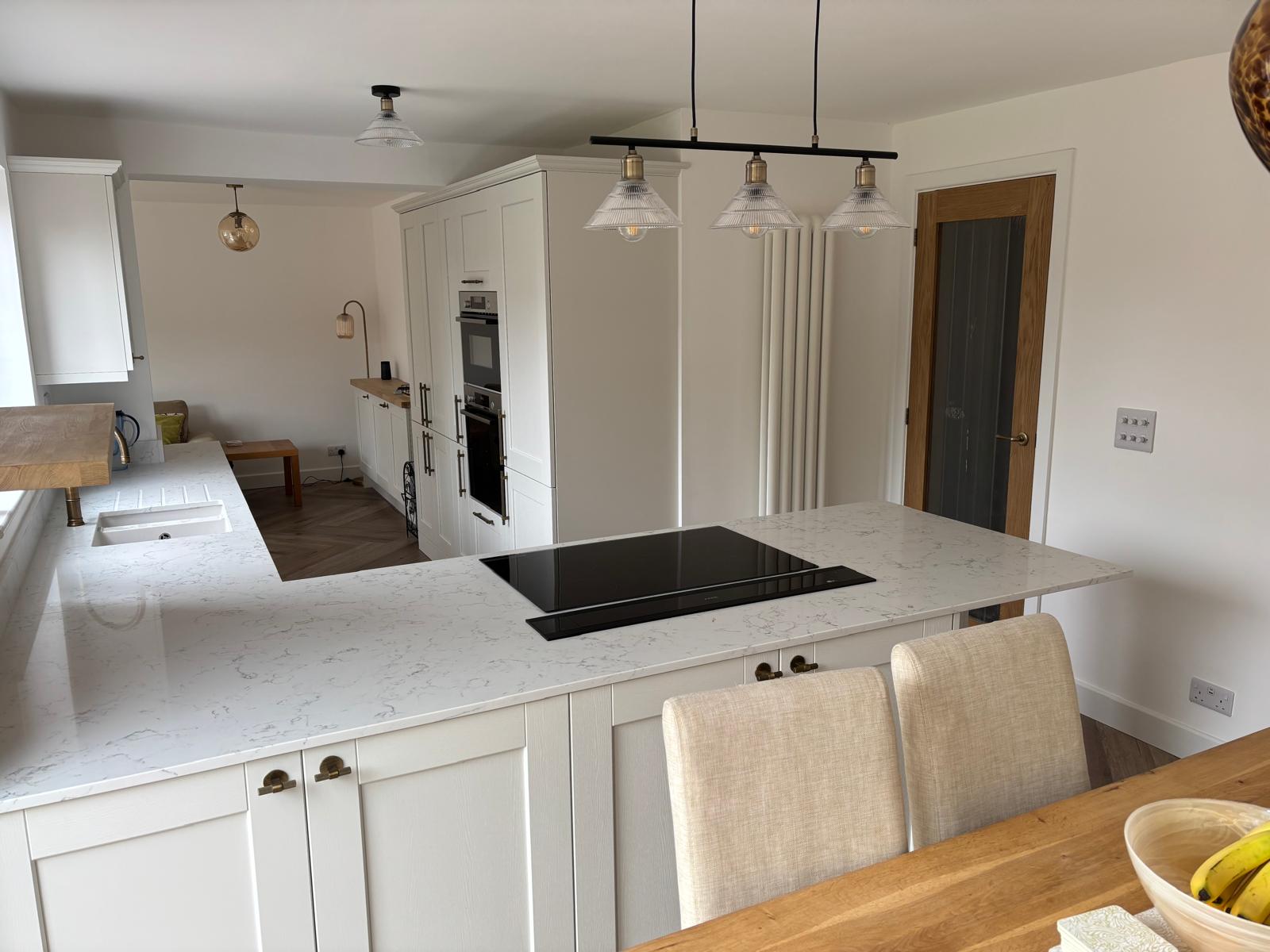 Modern open-plan kitchen with white cabinets, quartz countertops, induction hob island, and pendant lights