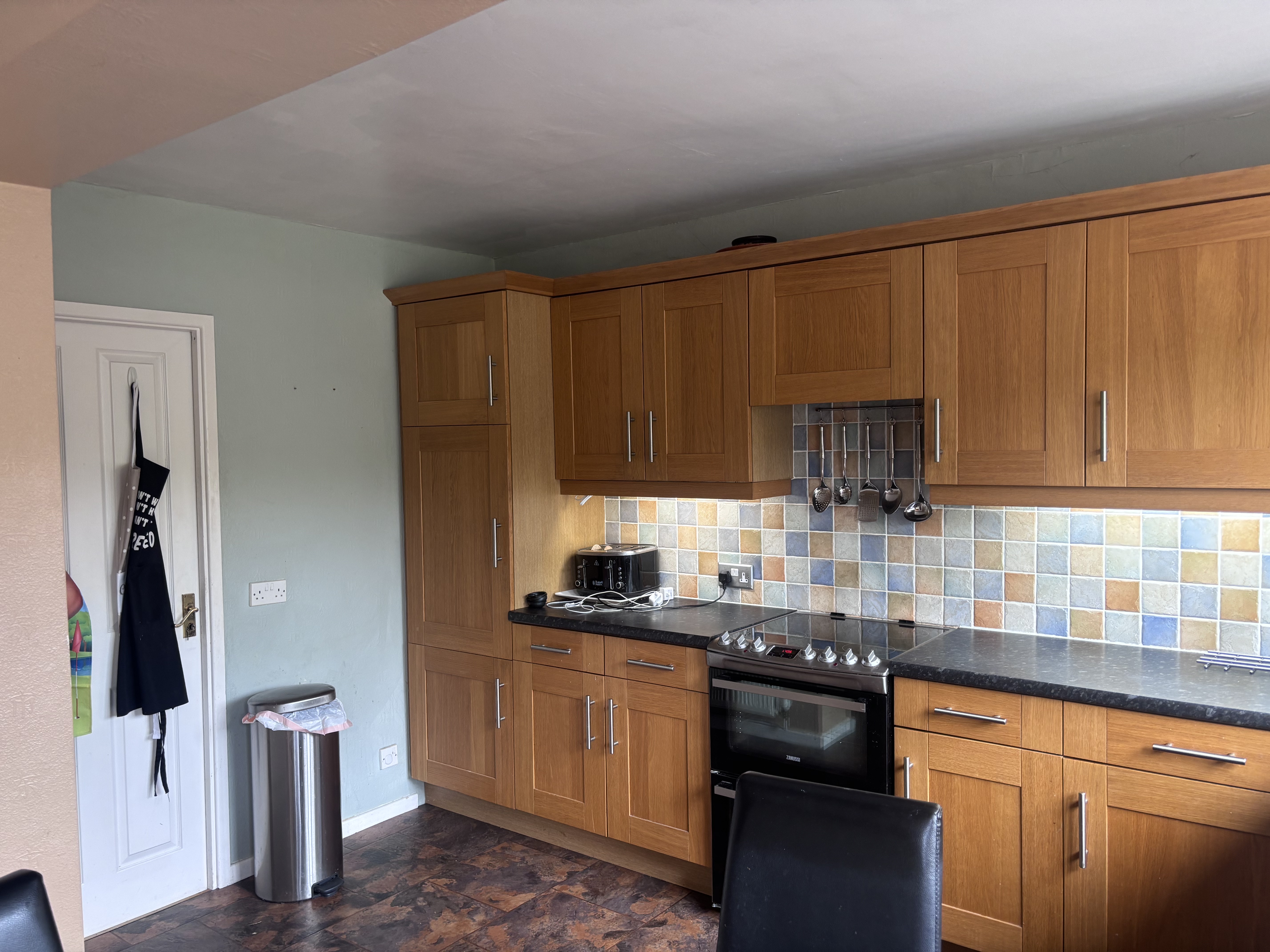 Old kitchen with wooden units and tiled splashback before modern renovation – Project Managed Kitchens.