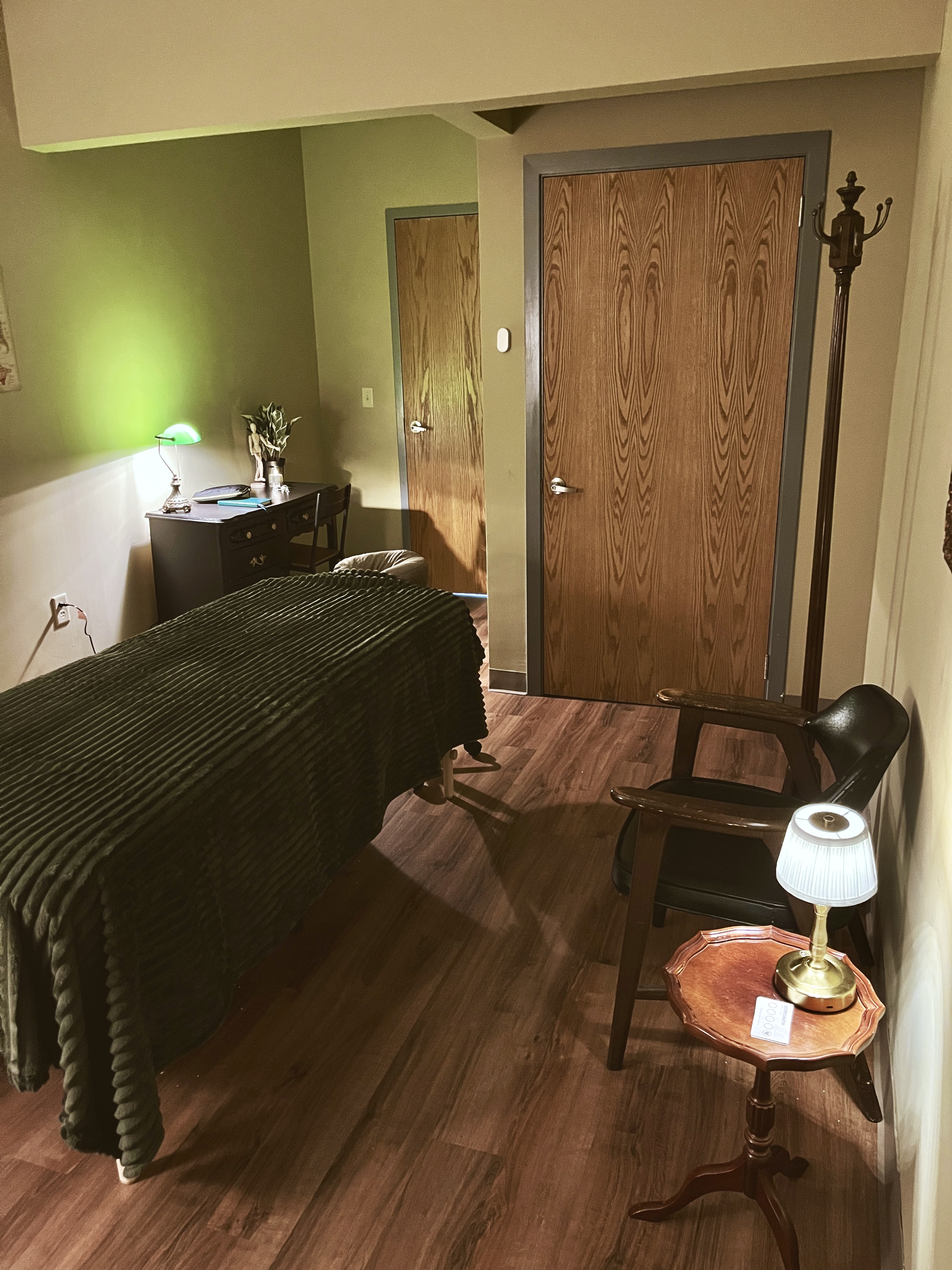 Milwaukee massage therapy room with earthy tones, anatomical posters, and a cozy green blanket on the massage table, creating a calm, grounded atmosphere