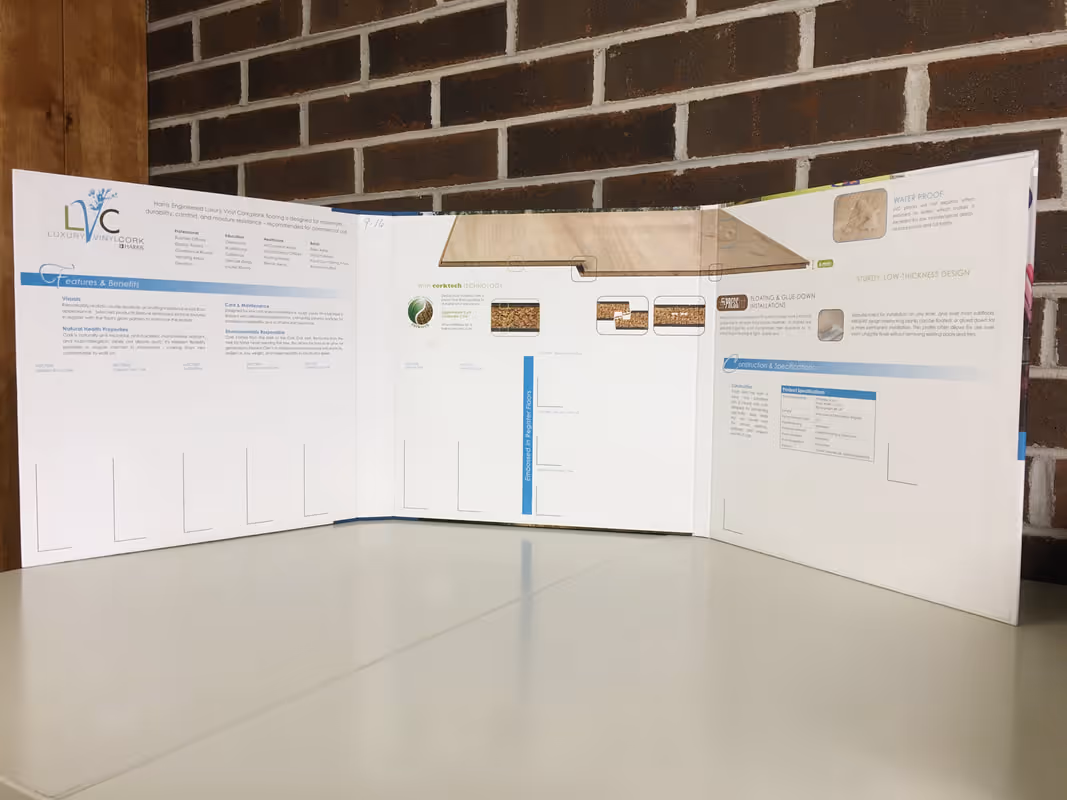 Open tri-fold brochure with text and images on a white surface against a brick wall.