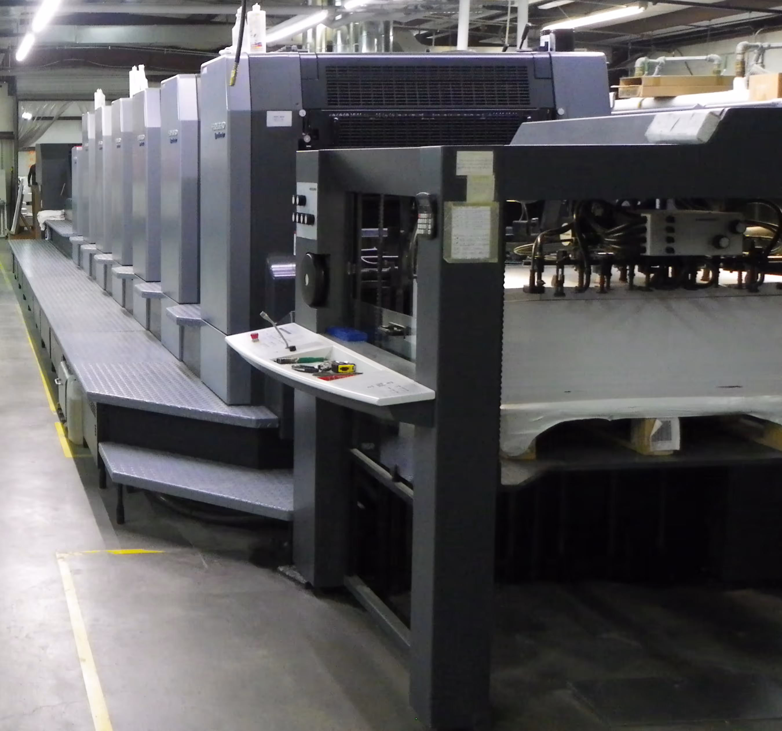 Large industrial six-color offset printing press in a factory setting.