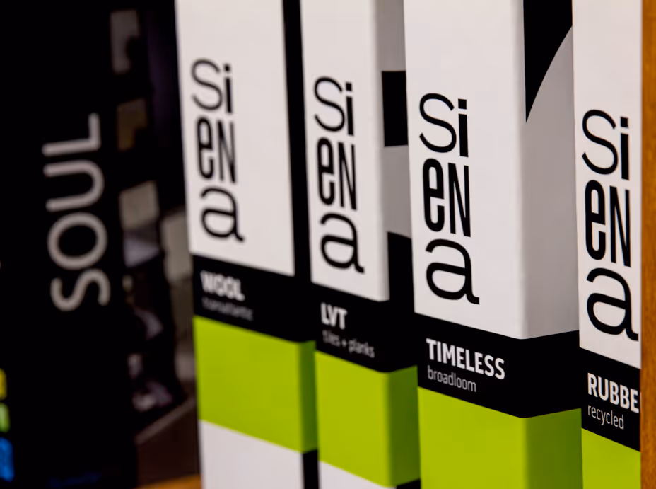 Close-up of four Siena brand product samples labeled wool, LVT, timeless, and rubber recycled.