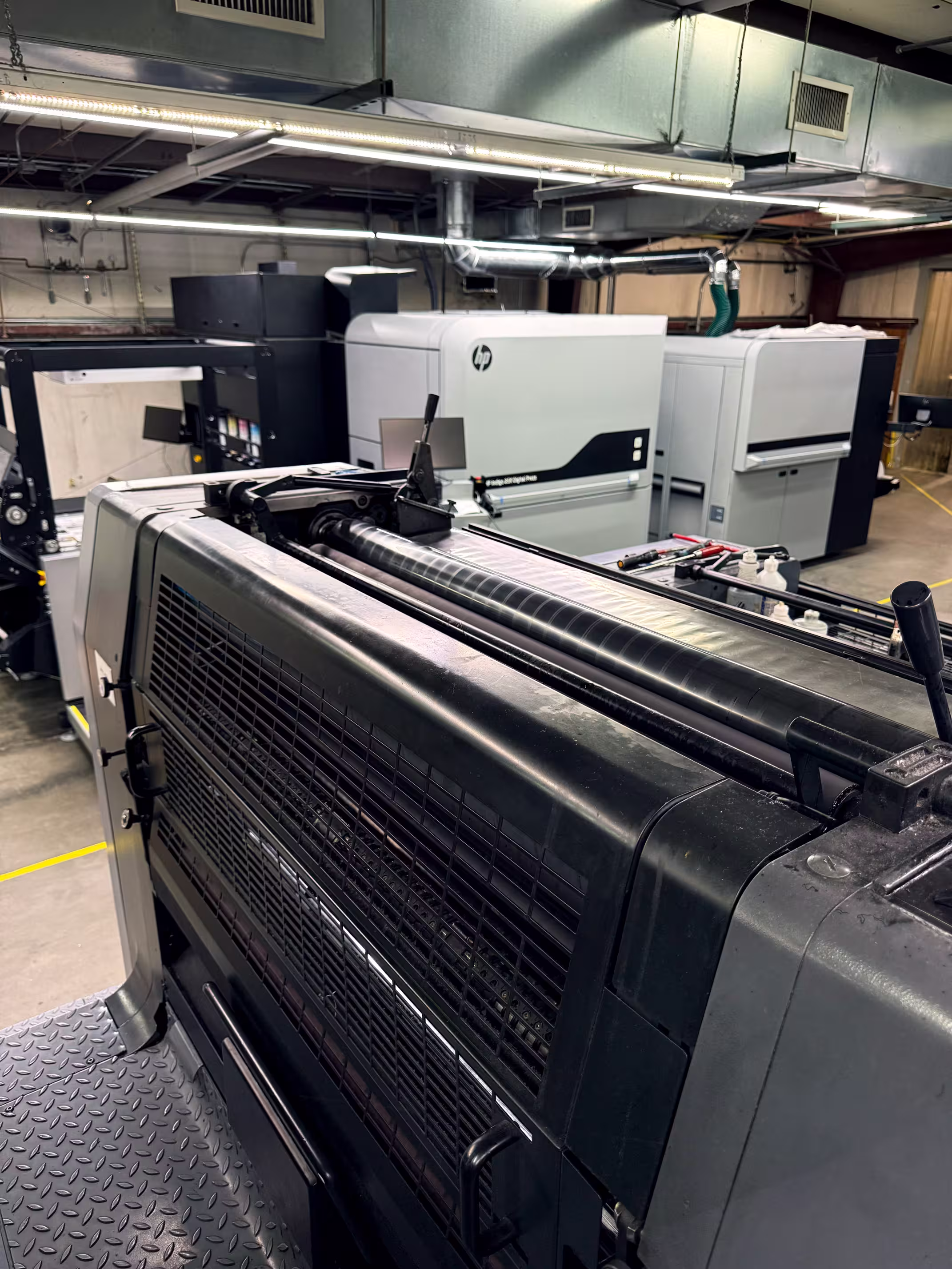 Close-up of large industrial printing machines in a factory with visible HP Indigo digital press printer.