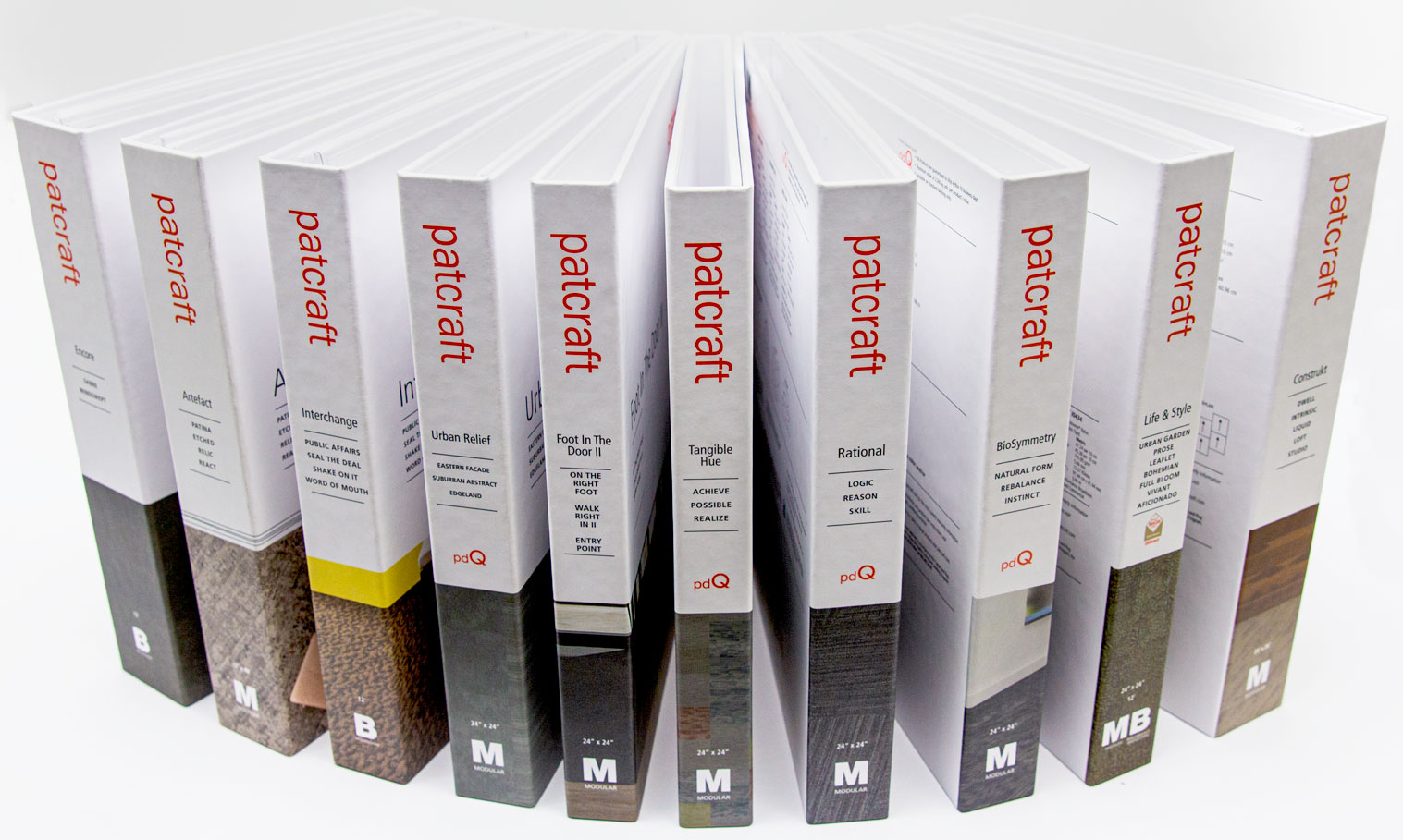 A row of eleven Patcraft sample binders with various textured covers and titles, fanned out on white.