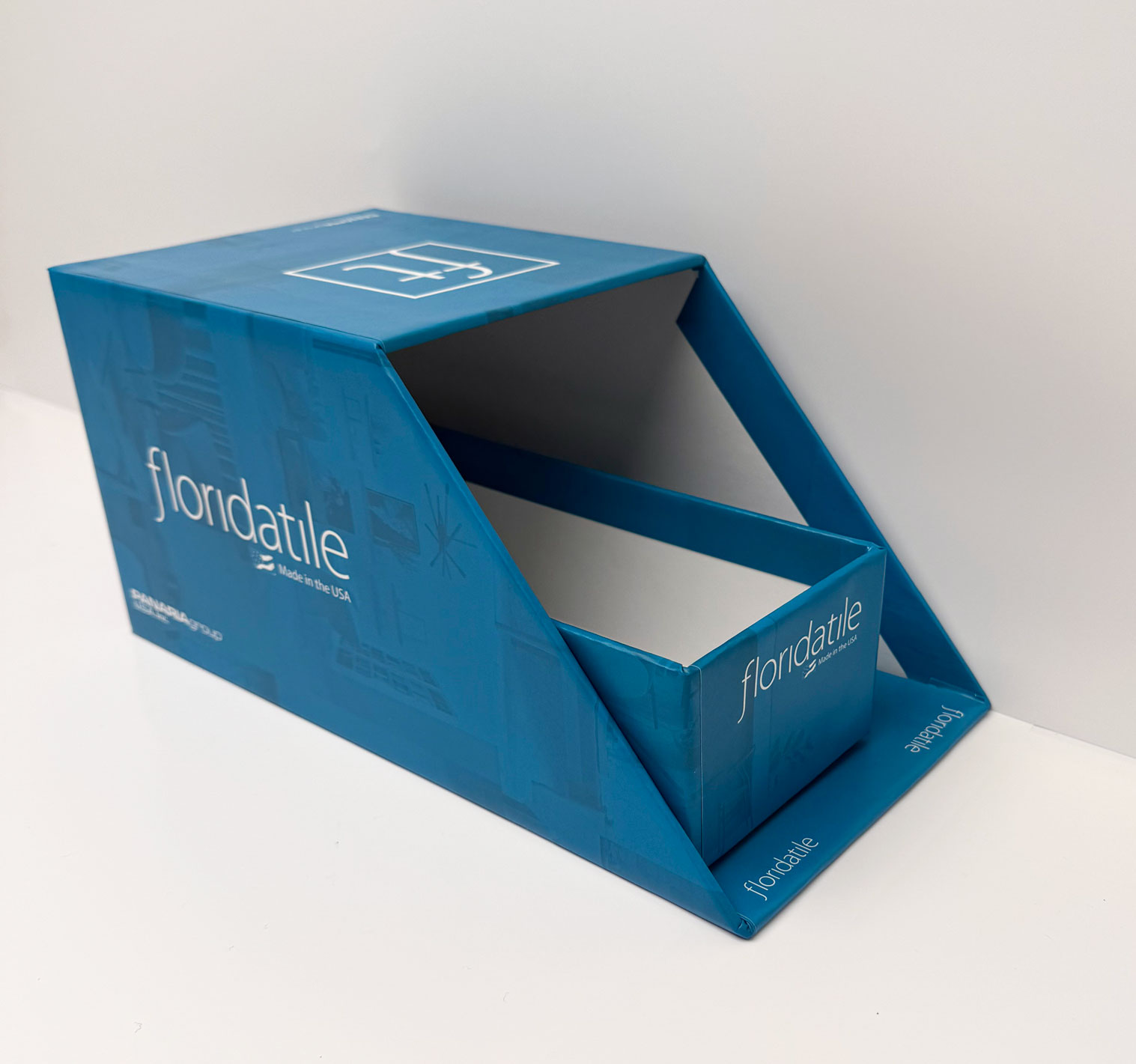 Blue open sample box labeled floridatile, made in the USA, on a white surface.