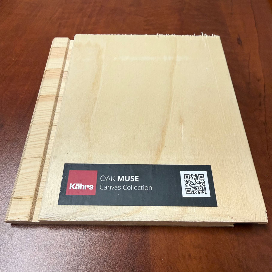 Wood sample from Kährs Oak Muse Canvas Collection on a brown surface with a QR code on label.