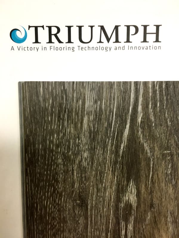 Triumph logo with slogan above a sample of dark wood flooring with a textured grain.