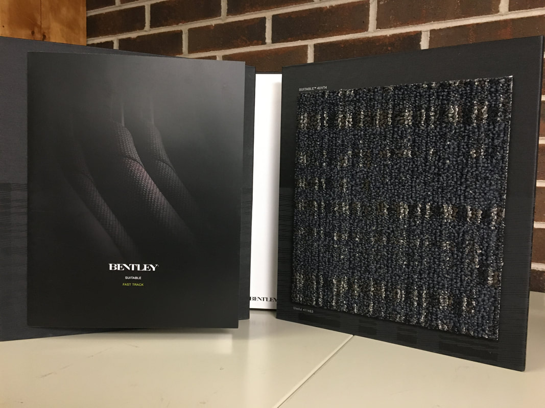 Bentley carpet sample booklet open to textured dark blue carpet swatch on table.