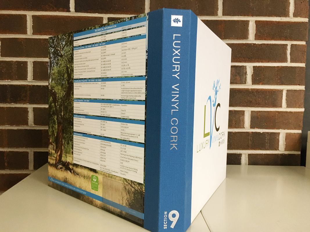 Open sample binder labeled Luxury Vinyl Cork with technical info chart on left page against brick wall background.