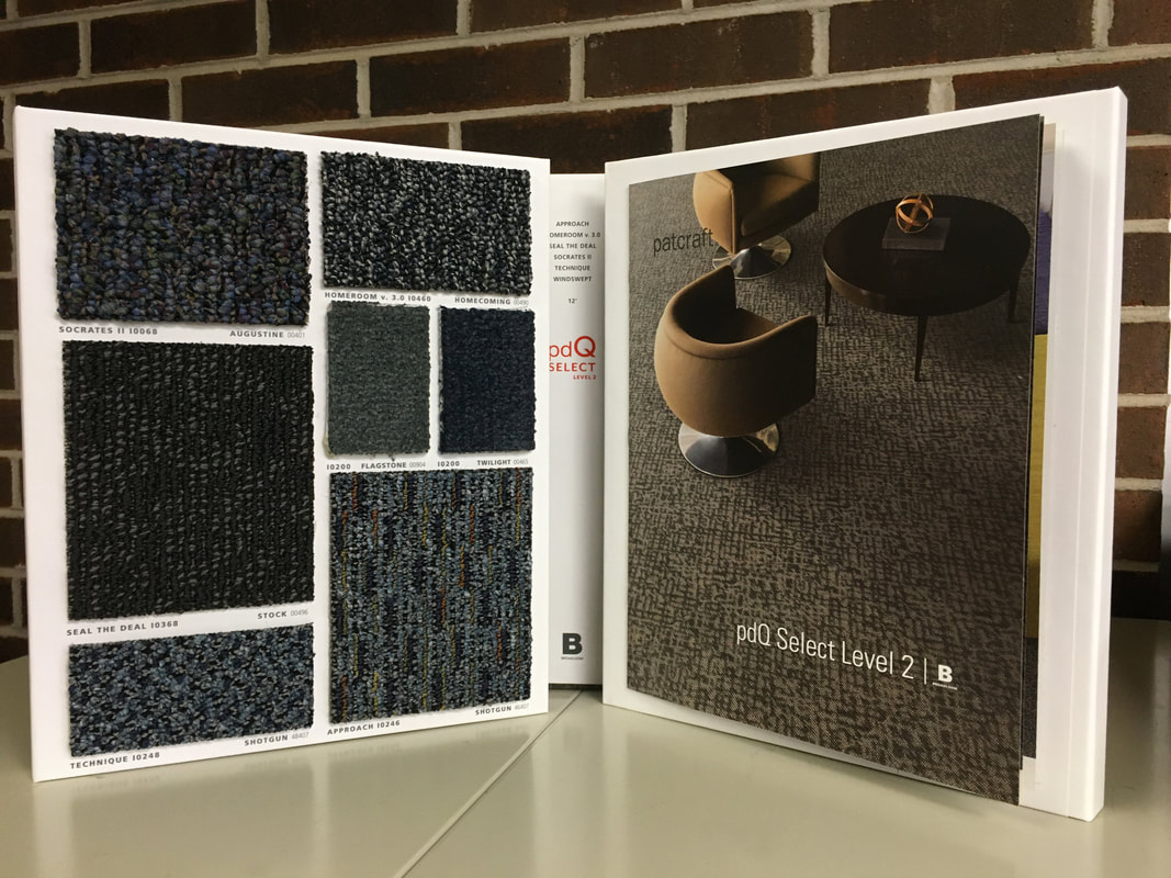 Open carpet sample books showing textured carpet swatches in dark neutral colors and patterns.