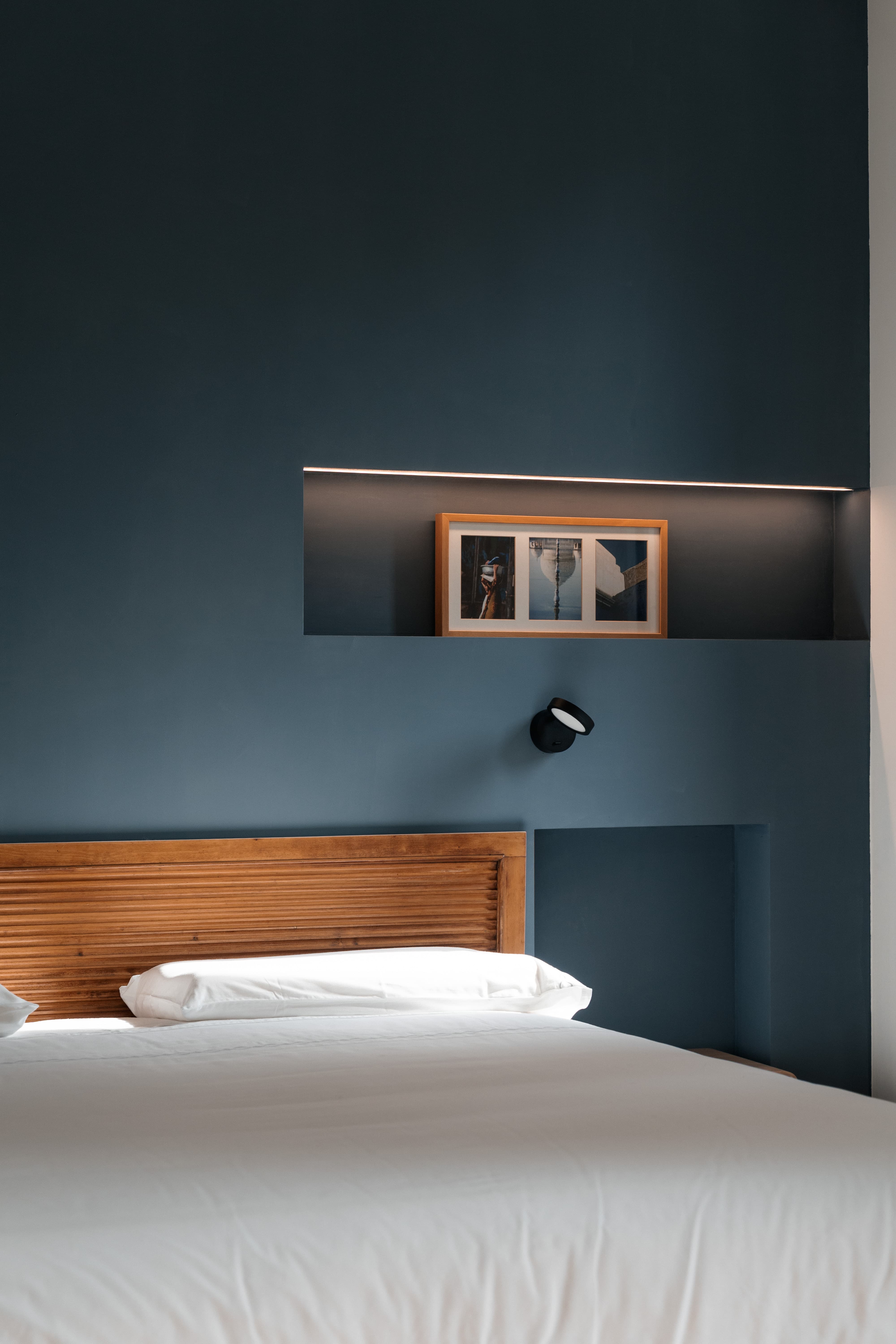 Dettaglio della camera Magnolia con pareti blu notte e letto matrimoniale.
