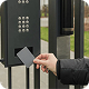 A person holds a key card up to an access control keypad on a gate for entry.