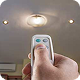 A person pointing a remote control at a ceiling light to operate it.